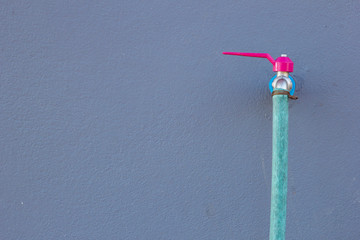 Faucets and hoses on gray wall.