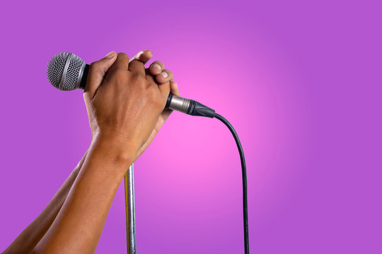 Hand holding a microphone on a stand.