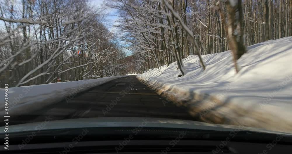 Wall mural driving on a scenic winter mountain road with snow and trees, beautiful sunny landscape, water drops