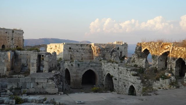 Static view of Krak des Chevaliers castle ruins with a partly cloudy sky in background