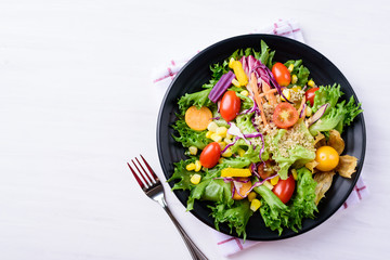 Healthy vegetables salad with quinoa seed and fork on white background, top view