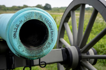 Looking down the green, weathered barrel of an old civil war cannon located in Gettysburg National Historic Battlefield in Gettysburg, Pennsylvania.