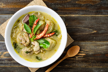 Thai green curry chicken in bowl and spoon on wooden background, Thai food, top view