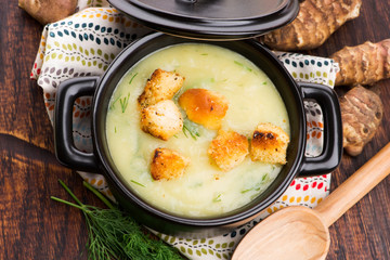 Creamy Jerusalem artichoke soup on wooden background
