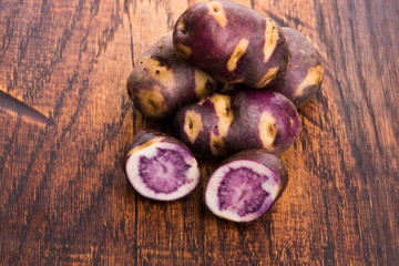 White - violet potato on wooden background. Organic plant