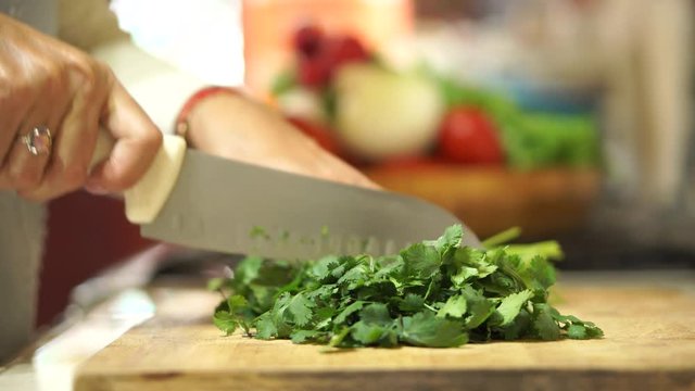 Latin woman cutting cilantro in kitchen