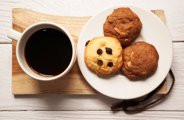 top view of a cup of hot americano or espresso coffee with chocolate chip and almond cookie on ceramic plate on white wooden background ,breakfast in minimal concept 