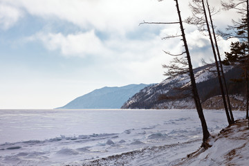 Baikal Lake in the winter season. Snow-covered beach and white snowy ice surface. Beautiful winter landscape