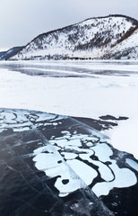 Fototapeta na wymiar Beautiful winter landscape of frozen Baikal Lake. The white bubbles of the bottom gaes froze into the ice with amusing natural patterns. Ice travel
