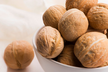 Walnuts in a white ceramic bowl on a white background