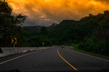 Naklejka premium Blurred background of a mountain road view, from a car windscreen that runs with care, with natural scenery surrounded by plants, large trees