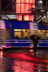 Stockholm, Sweden A woman with an umbrella in the rain at Sergels Torg and a city tram.