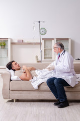 Obraz premium Old male doctor visiting young male patient