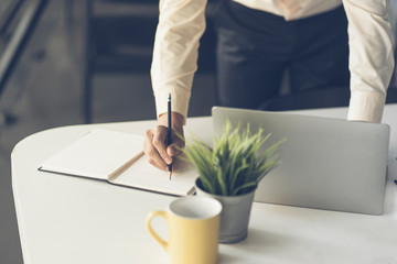 Close up of male hand writing with pencil on the book. Businessman working with data information in the office.