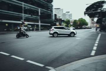 Car and motor cycle travelling around a corner with motion blur effect in the background