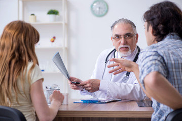 Young couple visiting old male doctor