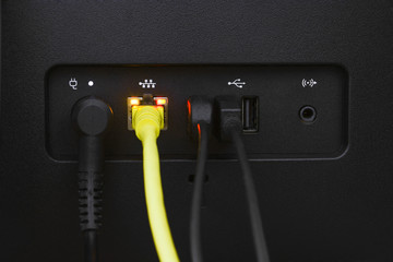 close up yellow LAN or network cable connected to a LAN port of personal computer (PC), computer...