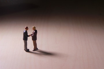 Obraz premium Dramatic Lighting, Simple Illustration Photo for Two Mini Figure Businesman Toy Handshaking for Business Agreement 