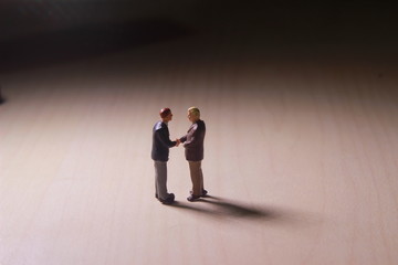 Dramatic Lighting, Simple Illustration Photo for Two Mini Figure Businesman Toy Handshaking for Business Agreement 