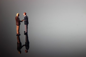 Dramatic Lighting, Simple Illustration Photo for Two Mini Figure Businesman Toy Handshaking for Business Agreement 