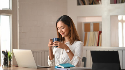 Coffee break, young creative woman holding coffee cup and smiling.