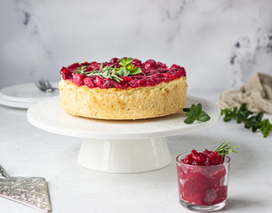 Classical New York cheesecake with cranberry sauce, mint and rosemary, light grey stone background. 