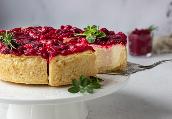 Classical New York cheesecake with cranberry sauce, mint and rosemary, light grey stone background. 