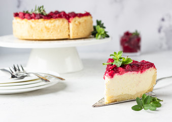 Classical New York cheesecake with cranberry sauce, mint and rosemary, light grey stone background. 