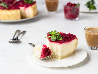 Classical New York cheesecake with cranberry sauce, mint and rosemary, light grey stone background. 