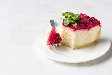 Classical New York cheesecake with cranberry sauce, mint and rosemary, light grey stone background. 