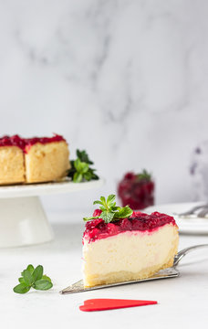 Classical New York cheesecake with cranberry sauce, mint and rosemary, light grey stone background. 