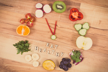 Fruits and vegetables in shape of clock showing time of 23 hours 55 minutes, new years resolutions concept