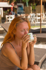 Young woman drinking coffee at the beach