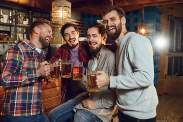 A group of friends is sitting in a bar with glasses of beer.