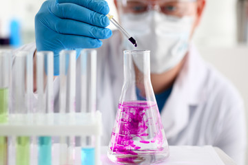 A male chemist holds test tube of glass