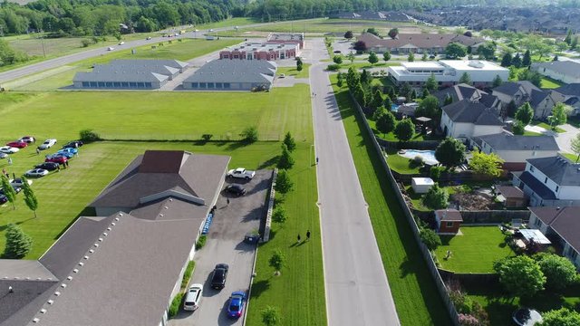 People Walking Down Road With Houses And Storage Units Summer Day Aerial