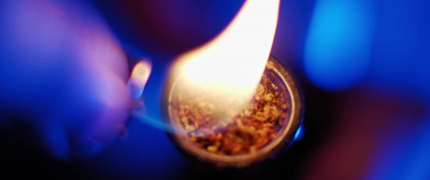 Cinematic close up, burning of cannabis, the process of smoking weed out of a bong, slow motion, dark blue room lighting, shallow depth of field, beautiful bokeh. BMPCC 4K