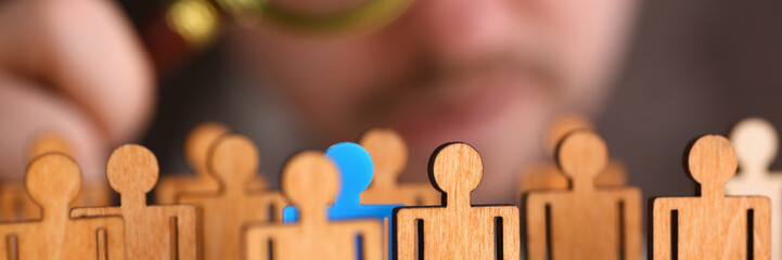 Man in suit look thru loupe on statuettes closeup