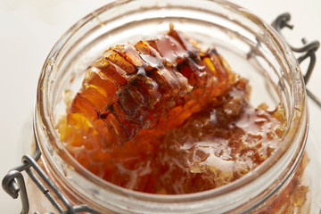 Honeycomb in glass jar on white background 