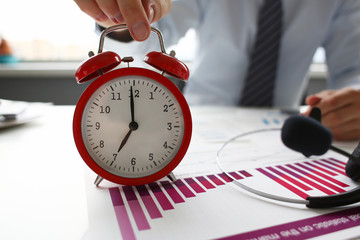 Male hand on the alarm clock a red color stands