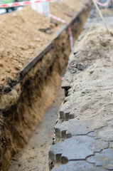 Empty trench along the pedestrian sidewalk. A narrow trench was dug for laying a power electric...