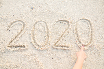 Fototapeta na wymiar Hand writing 2020 Happy new year message on the sand beach.