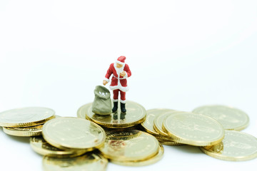 Miniature People : Santa in whith cloth with bag standing on the coins using as merry christmas and new financial concept.