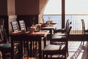 Shallow depth of field (selective focus) image with tables in a restaurant at breakfast early in the morning