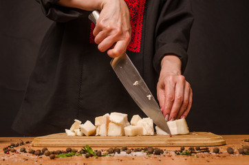 A woman is cutting smoked meat into the kitchen.