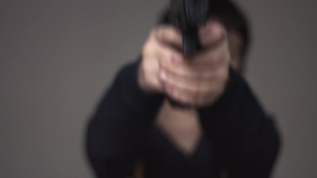 Blurred anonymous young boy silhouette loading and pointing a nine millimeter toy gun perfect replica at the camera then pulling the trigger