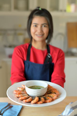 Asian women carrying dishes of Baked salted shrimp and spicy seafood sauce