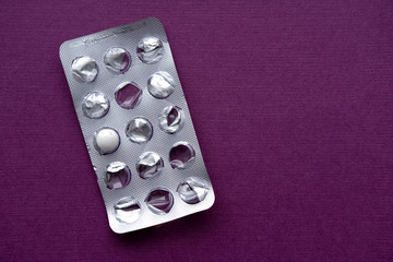 Used blister pack of pills on purple background. Copy space.