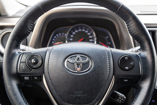 The interior of the car Toyota Rav4 with a view of the steering wheel, dashboard, seats and multimedia system with black leather trim and the letter-shaped emblem