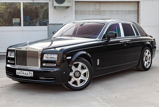 Front view of new a very expensive luxury Rolls Royce Phantom car, a long black limousine, model outdoors, prepared for sale with shining sunlight